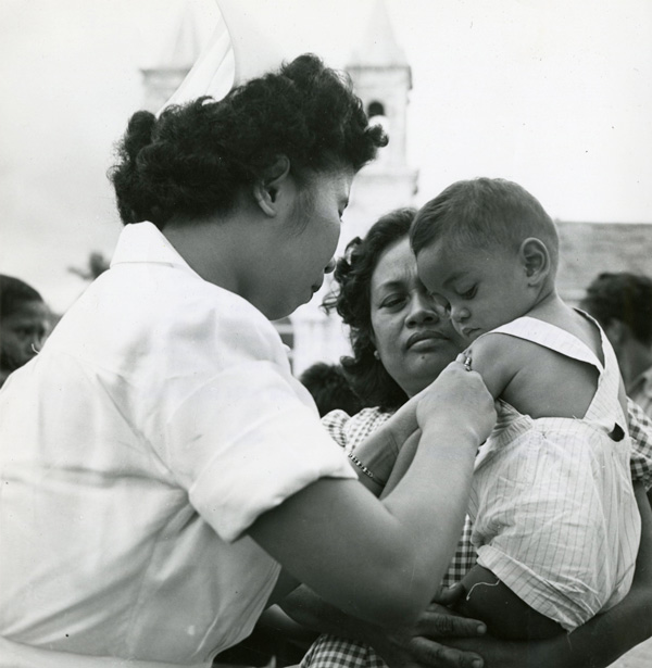 A woman holds a child getting a shot on the upper left arm.