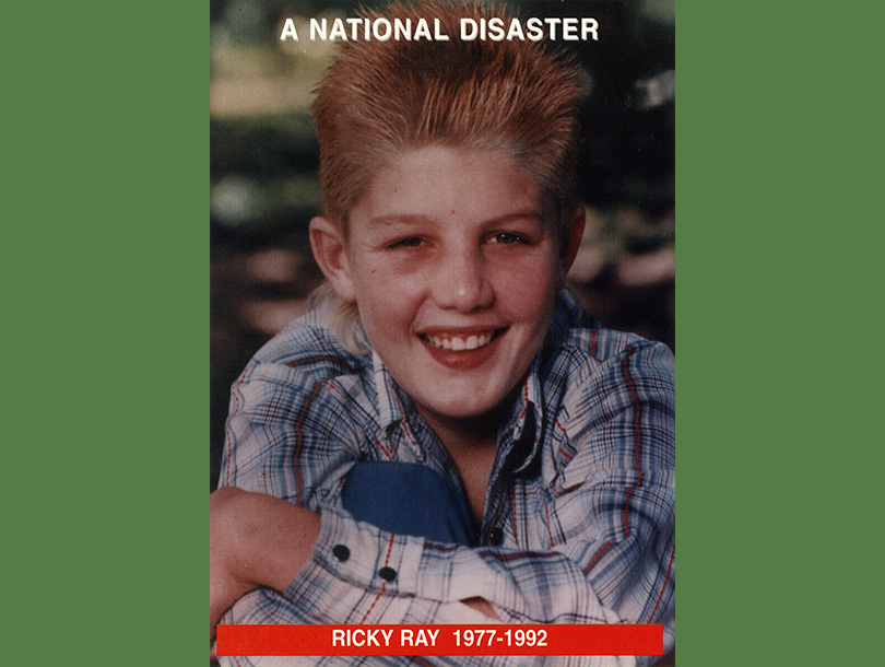 Color photograph of a smiling white boy (Ricky Ray) sitting in the grass