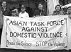 Seven Asian American adults and children stand holding a banner and looking at the viewer.