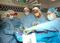 Five members of a surgical team in an operating room with surgical instruments in the foreground. 