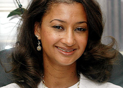 A woman smiling in white medical coat.