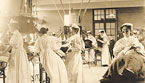 Groups of White female nurses, some wearing goggles, administer treatment to patients.