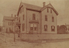 A large house on a corner lot with a picket fence around the yard.