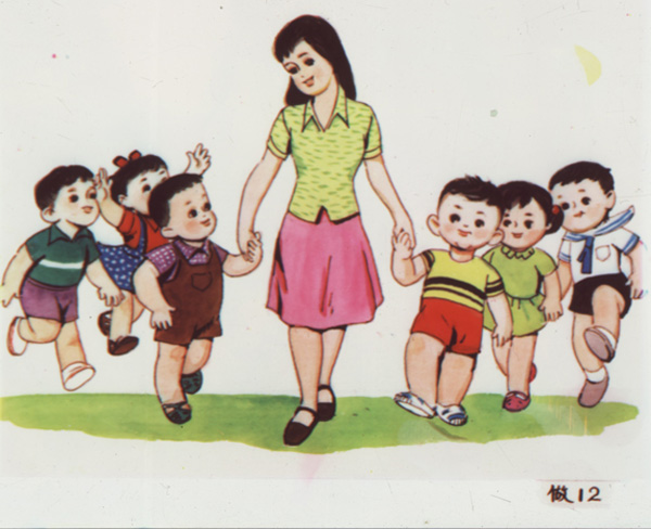 Slide showing a teacher, in a red skirt and green blouse, walks along holding the hands of two little boys who skip merrily beside her, with other children flanking both boys